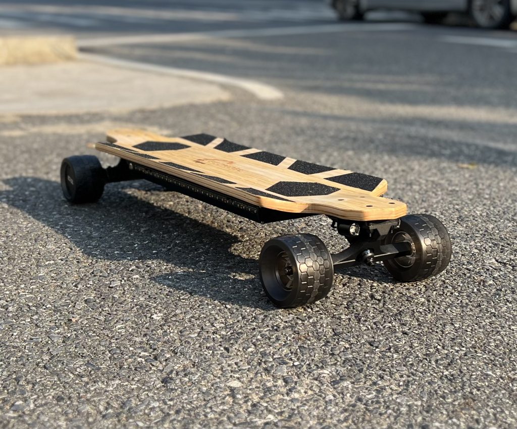 A mini electric skateboard on a paved road.
