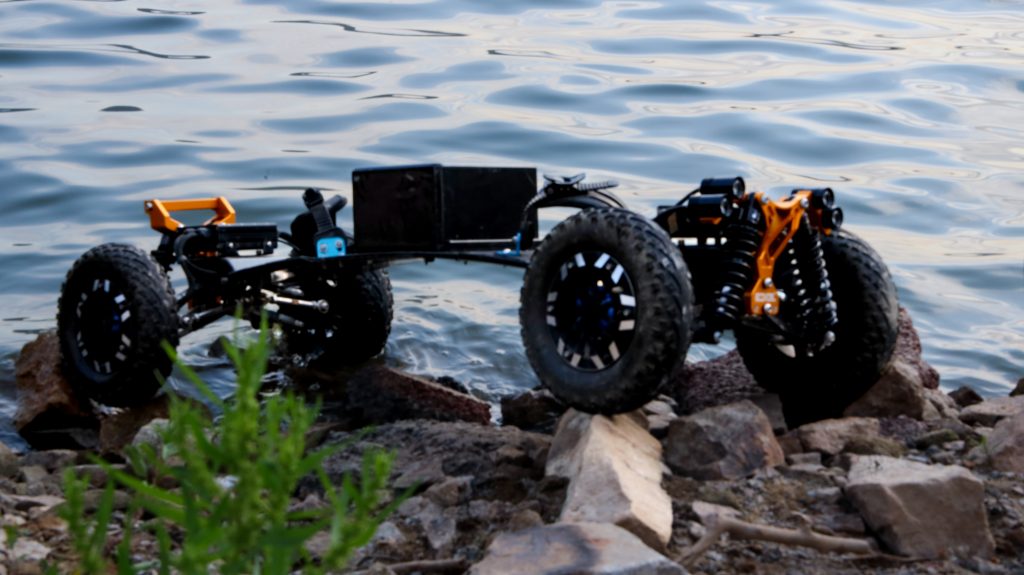 Off-road electric skateboard on rocky terrain by the water.