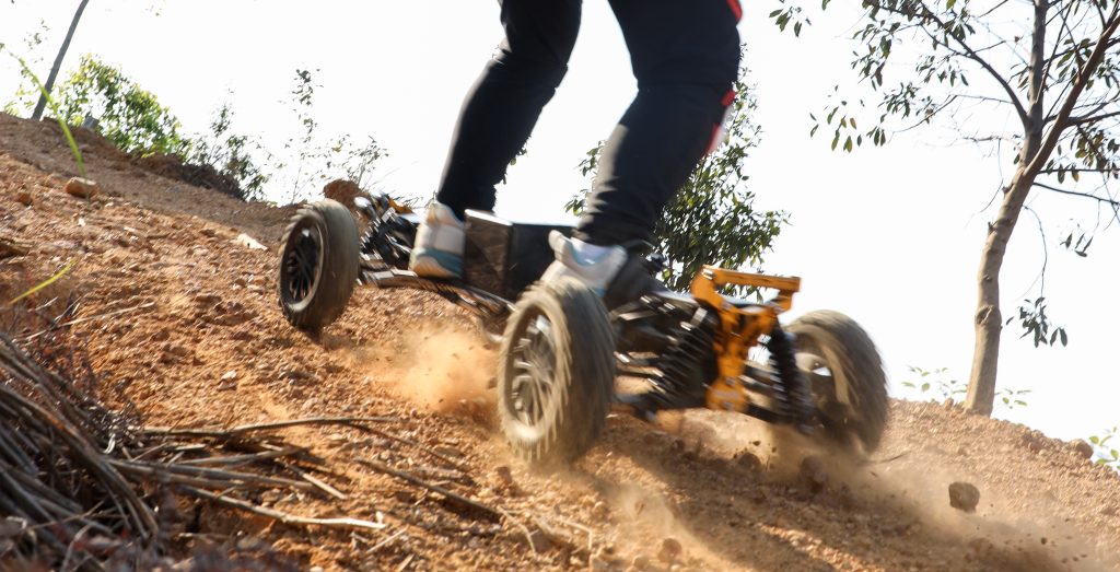 Rider enjoying an electric skateboard on a dirt path through the forest