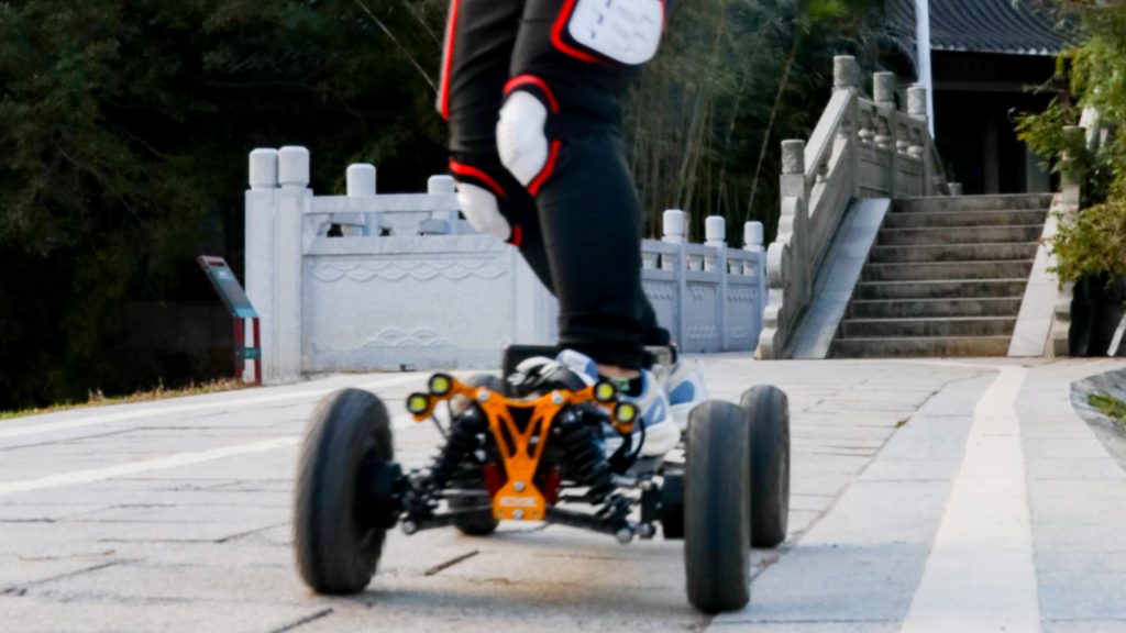Person riding an off-road electric skateboard on a stone path.