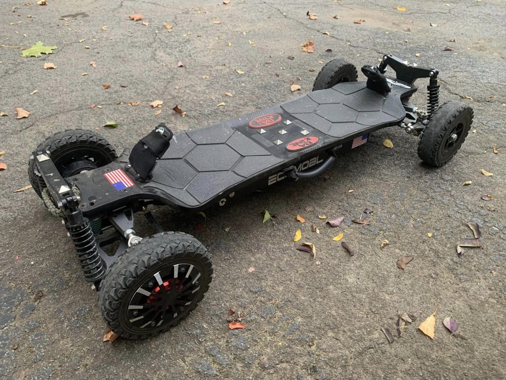 Electric skateboard with rugged tires on a paved surface.