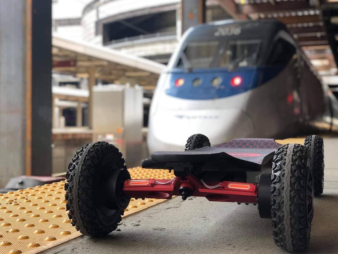 Electric skateboard near a train at a station platform.