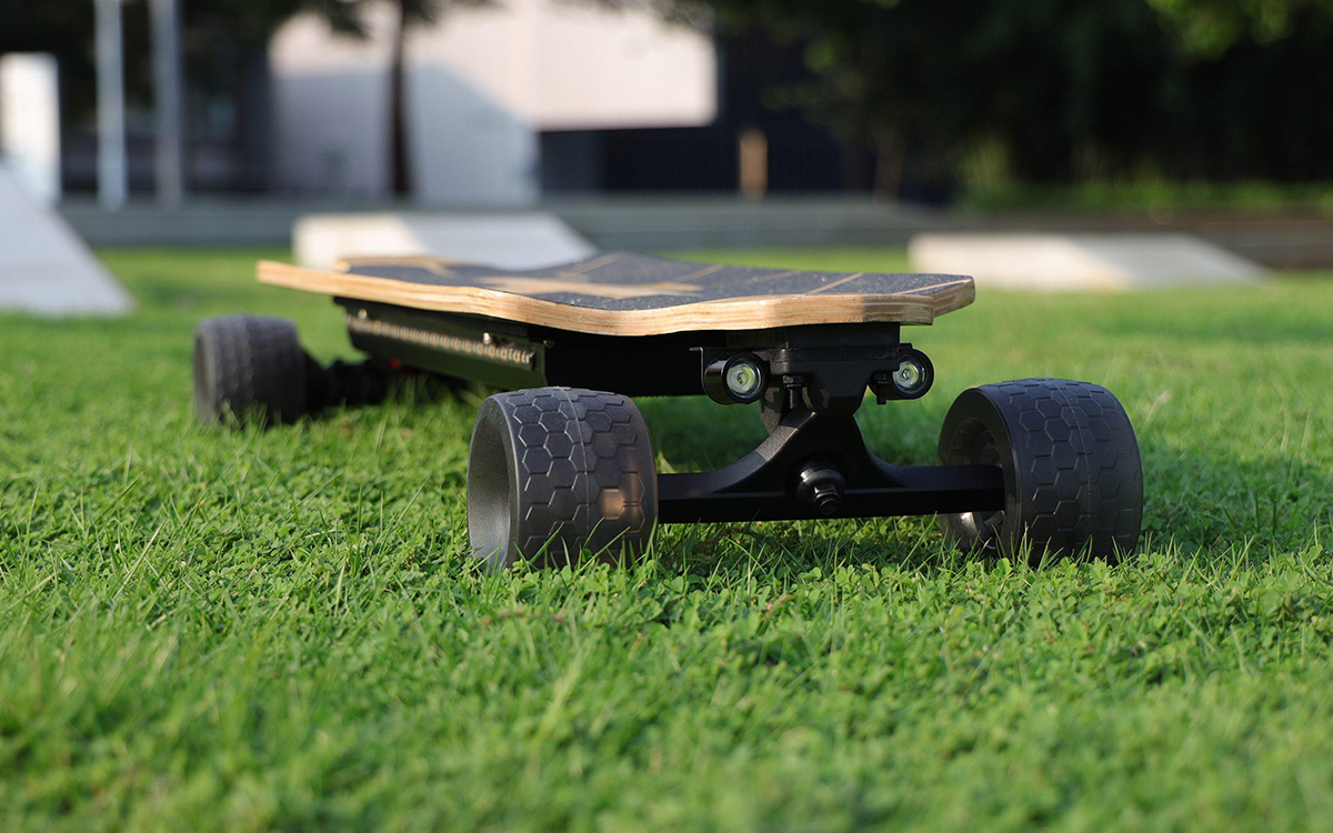 Electric skateboard on grassy field.